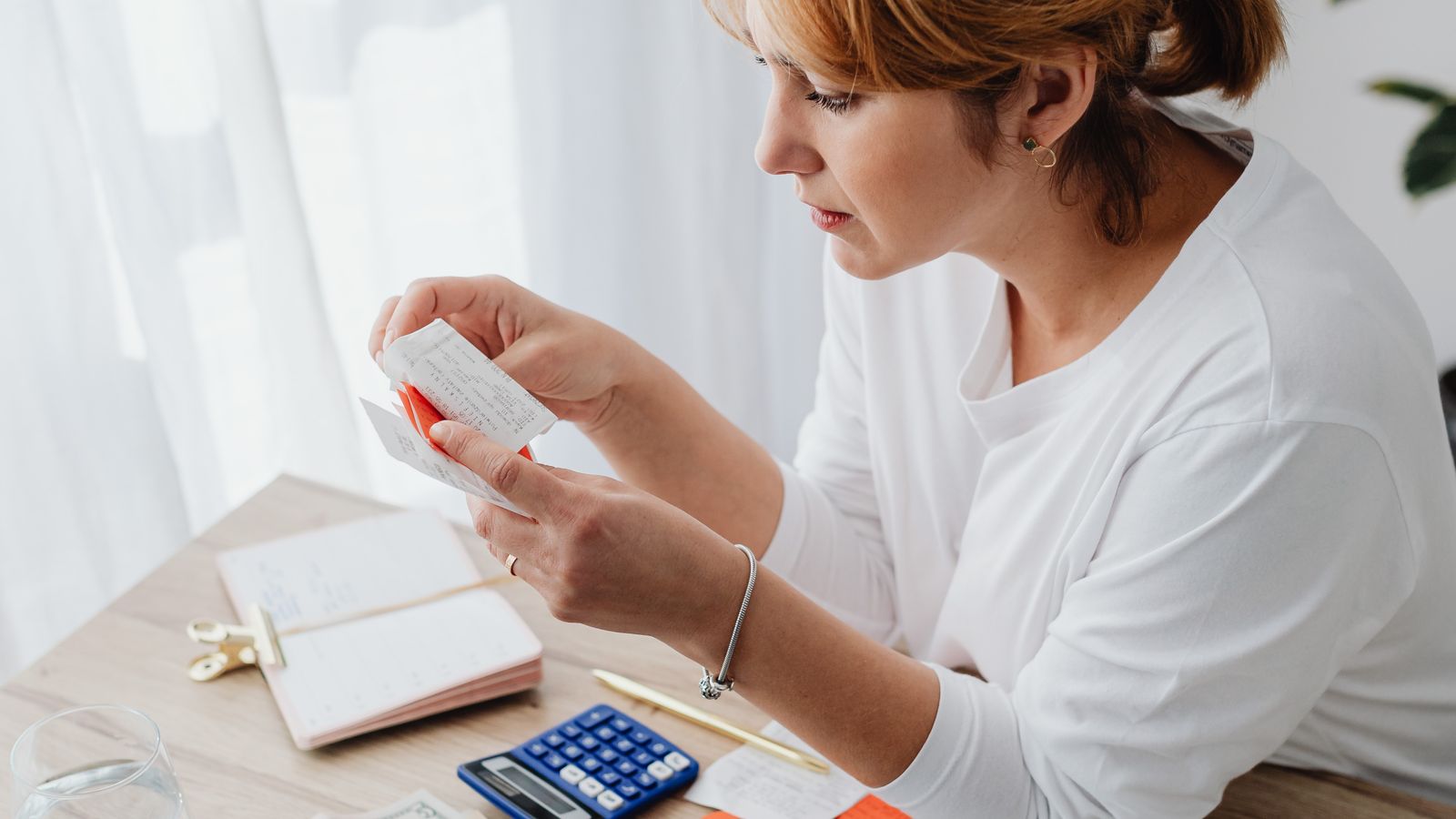 Mujer calculando su presupuesto con un portátil, recibos y una calculadora